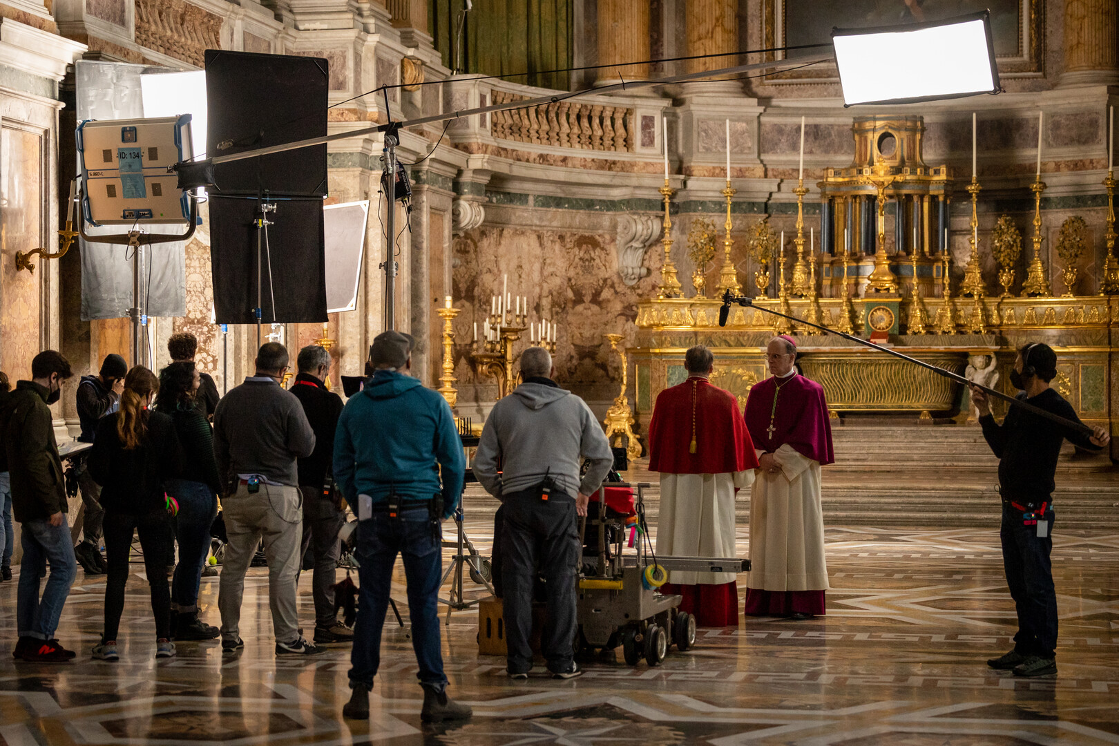 a film crew and actors in front of a cathedral altar