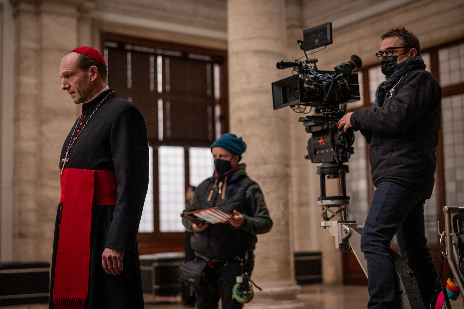 Actor Ralph Fiennes facing left with director of photography Stéphane Fontaine filming him from behind