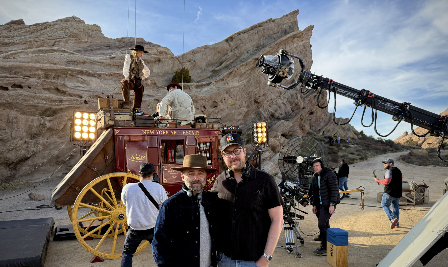 Male and femail stunt performers on top of a horse drawn carriage on the set of a western movie