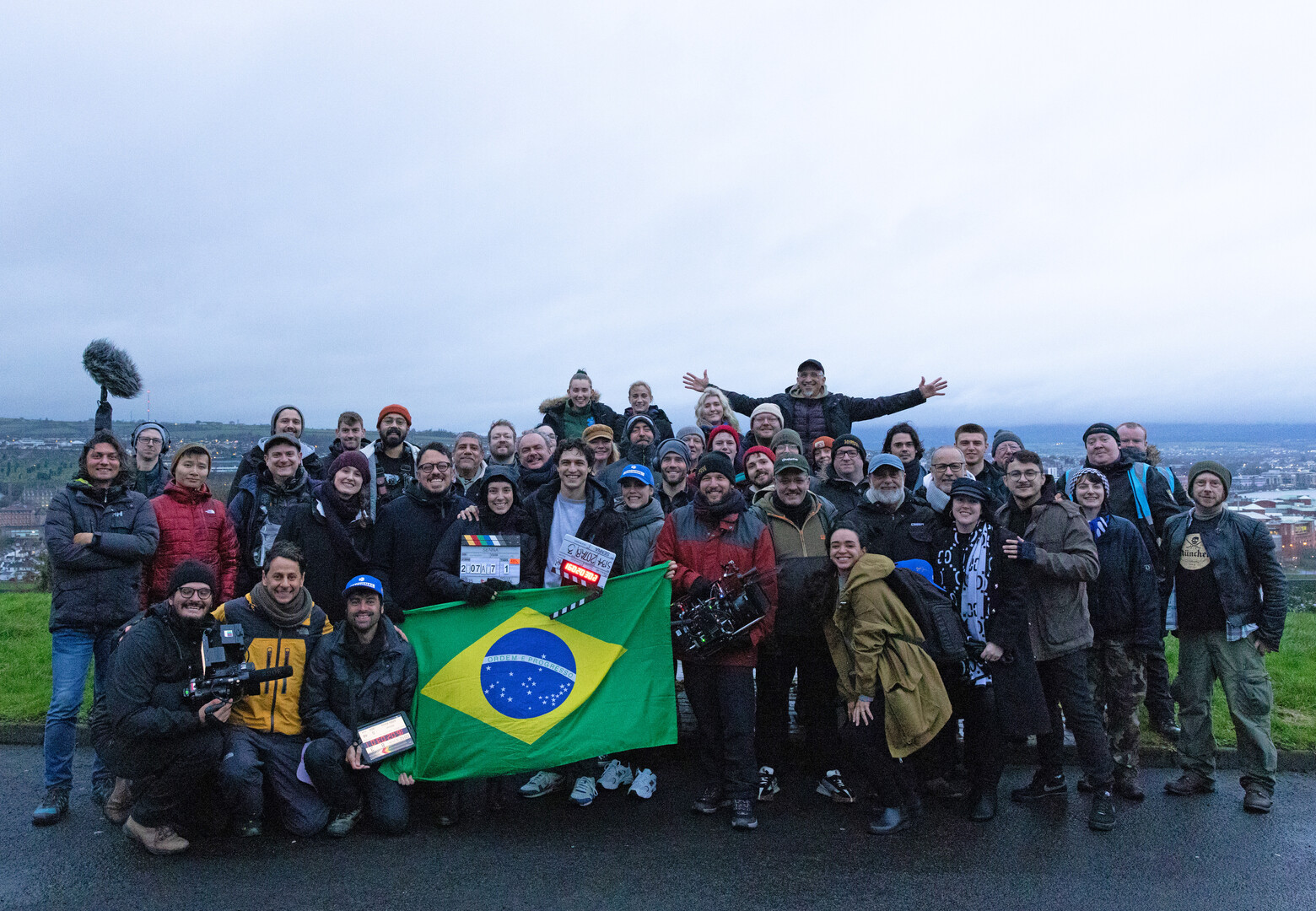 the entire film crew in a large group photo holding a Brazilian flag