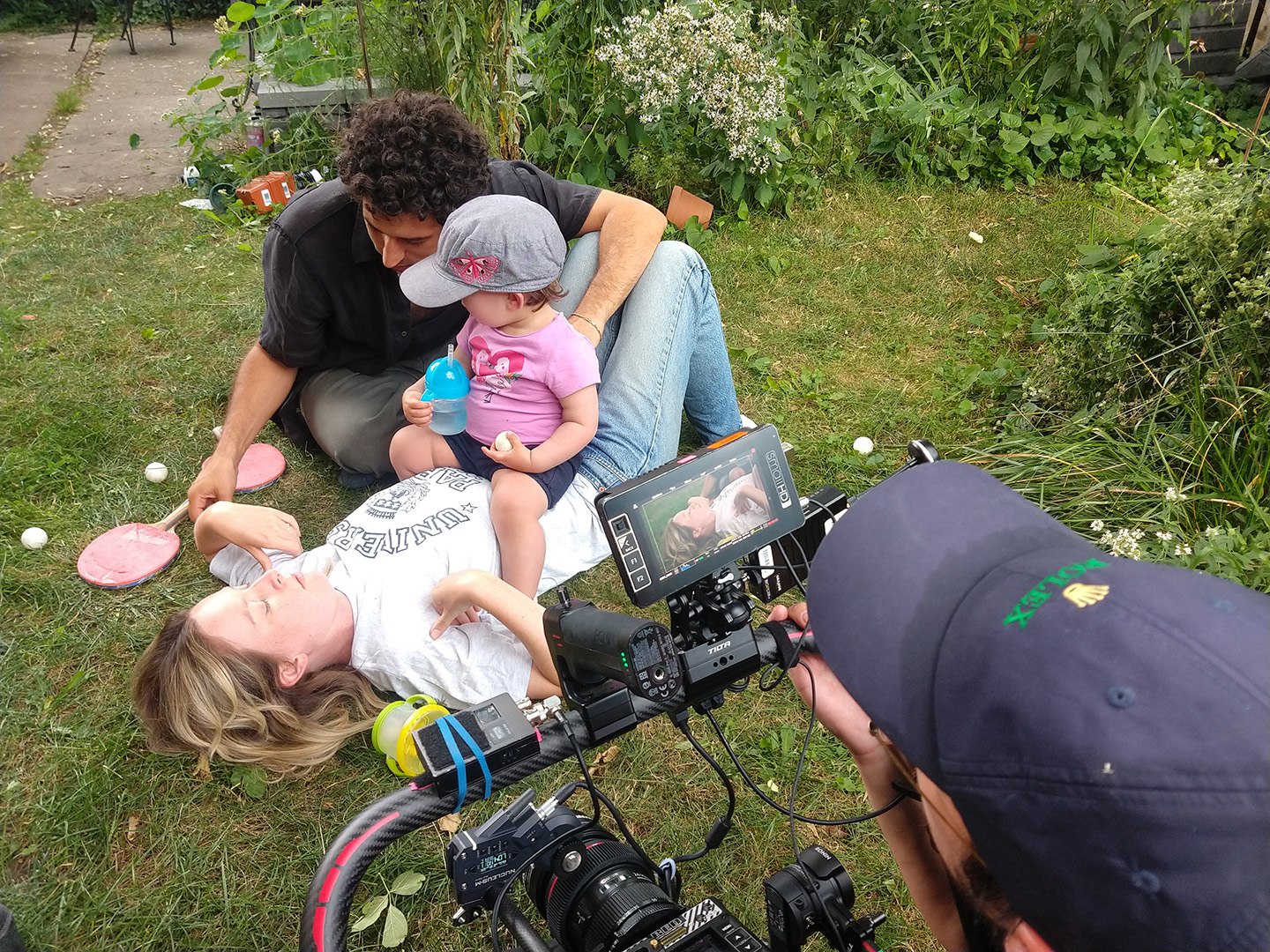 a woman being filmed lying on her back with a toddler sitting on her stomach