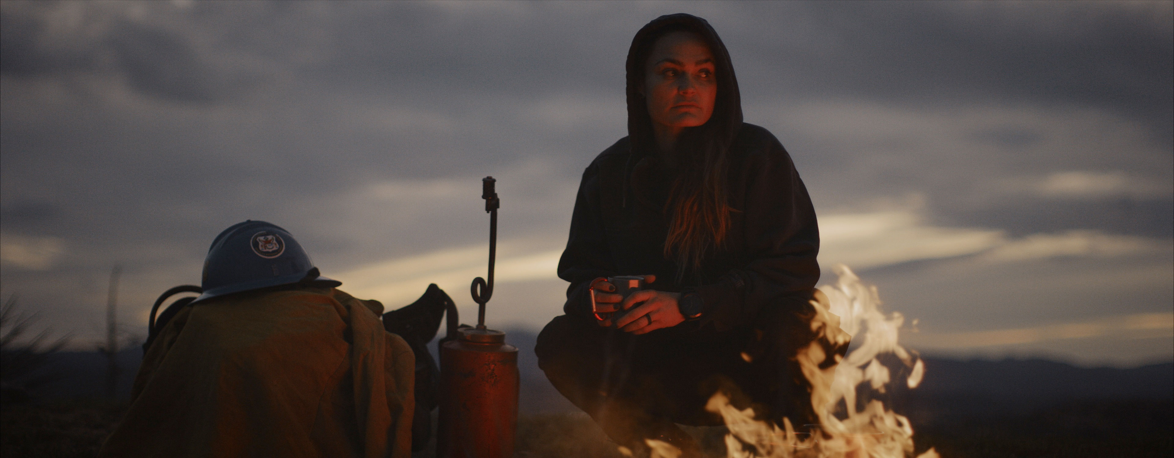 woman holding a cup near a campfire