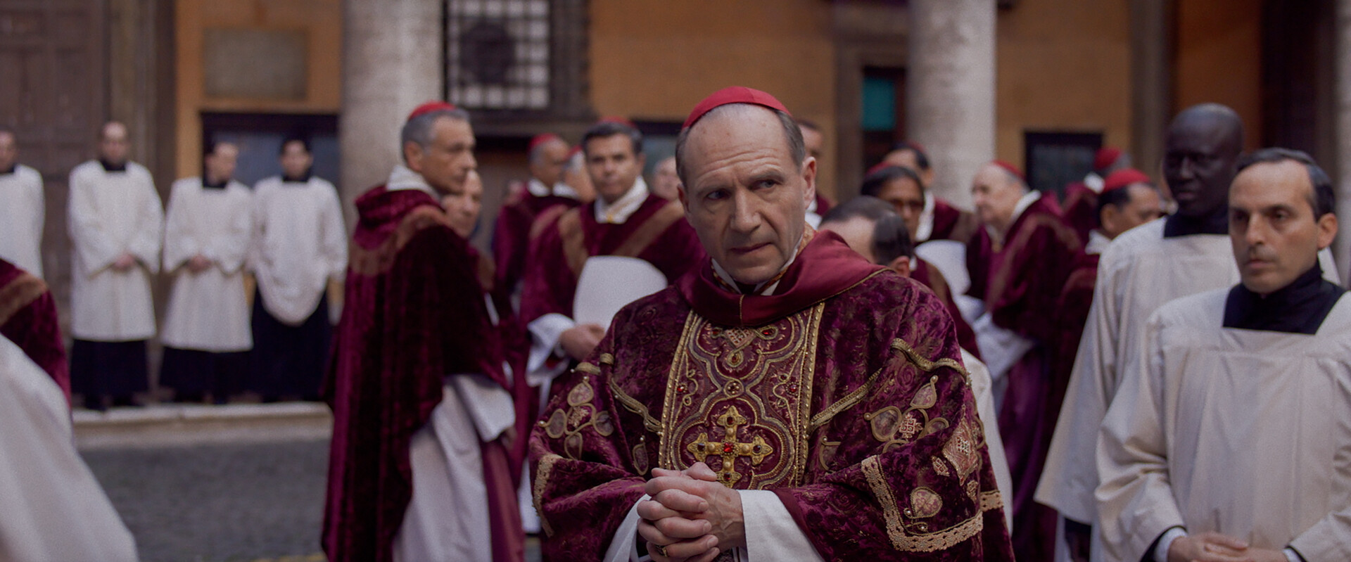Actor Ralph Fiennes on set in costume facing the camera with a pensive expression