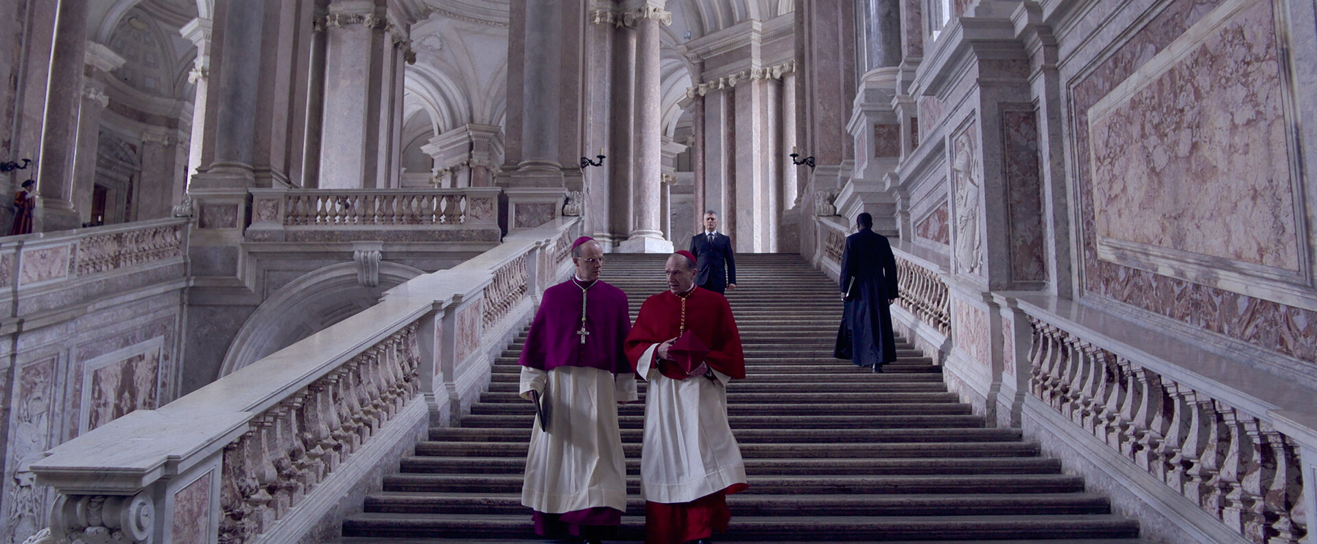 two bishops walk down a large marble staircase