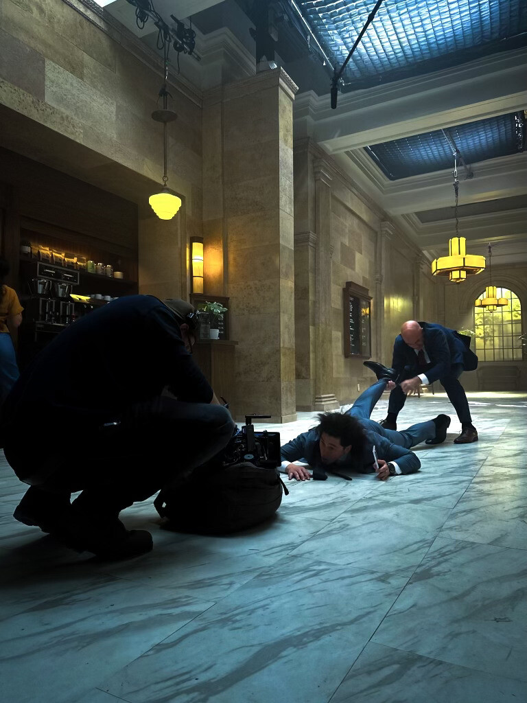 Two stunt performers filming a fight scene in front of a camera operator filming at a low angle