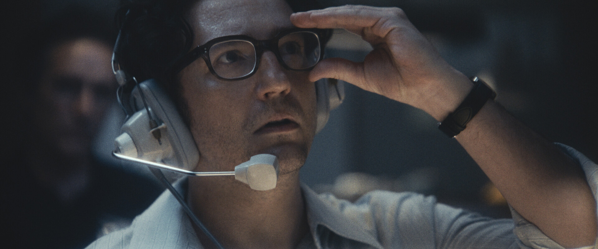 close up of a man with glasses wearing a headset