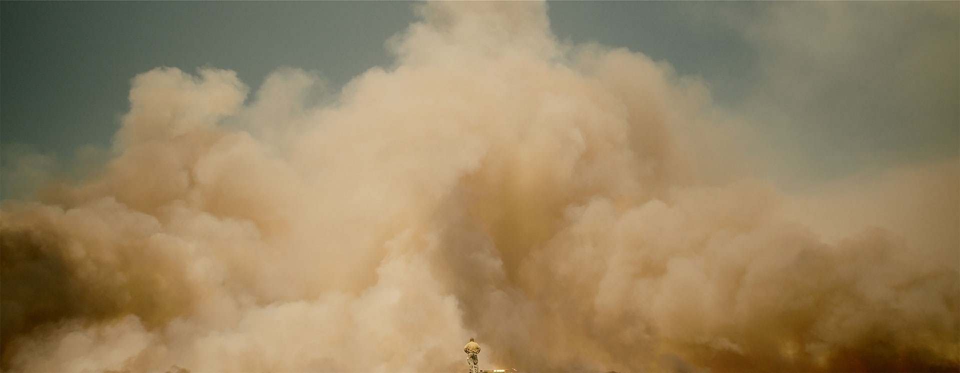 large smoke cloud with a tiny human figure in the center