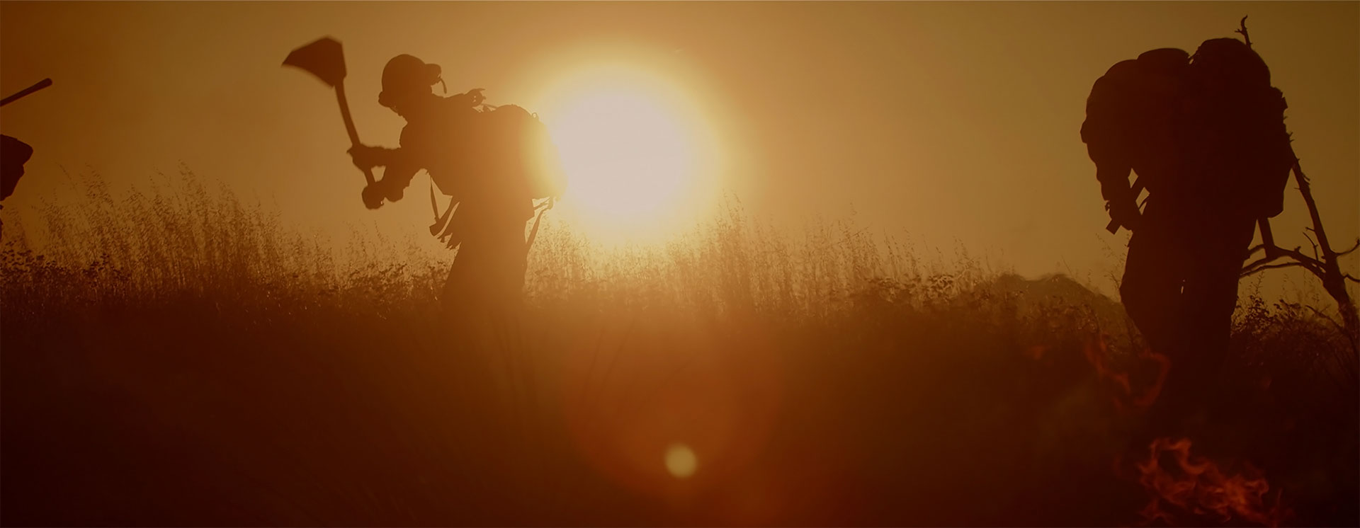 firefighters using tools in front of a sunset